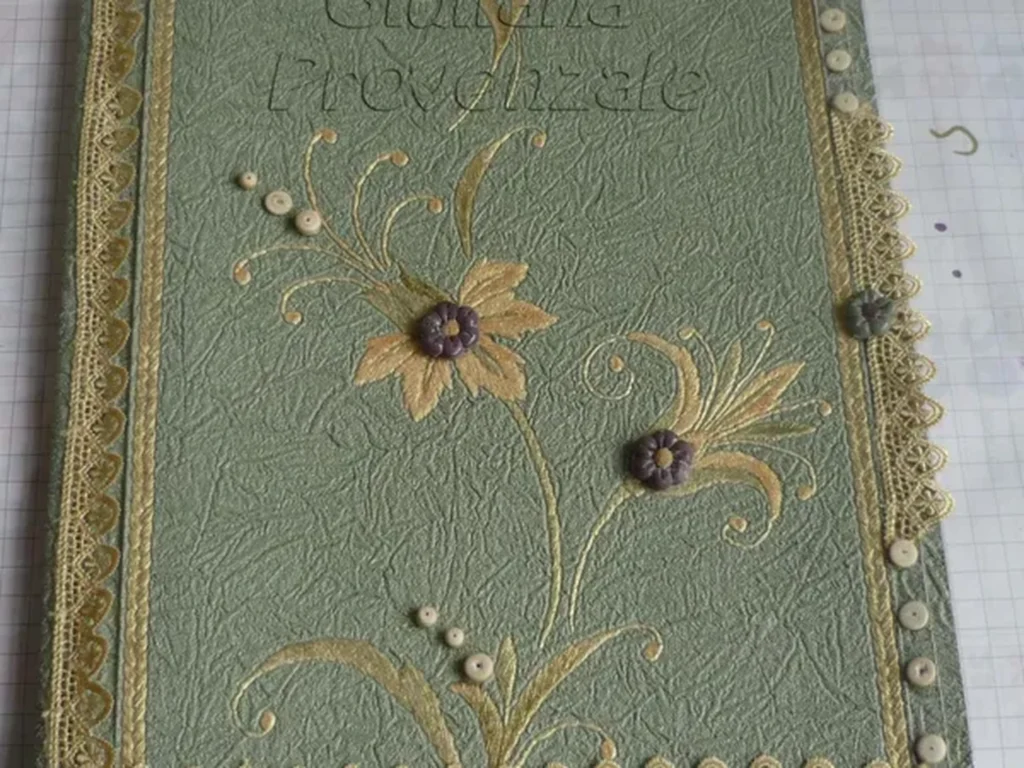 Dettaglio di un quaderno artigianale con copertina in carta da parati texture vintage e colori caldi.